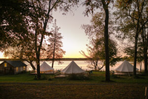 Lakecroft glamping view of three lakefront bell tents while the sun sets